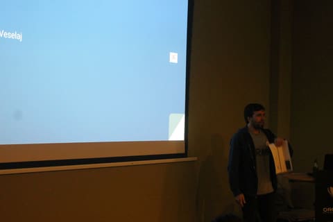 A speaker beside the screen during a talk